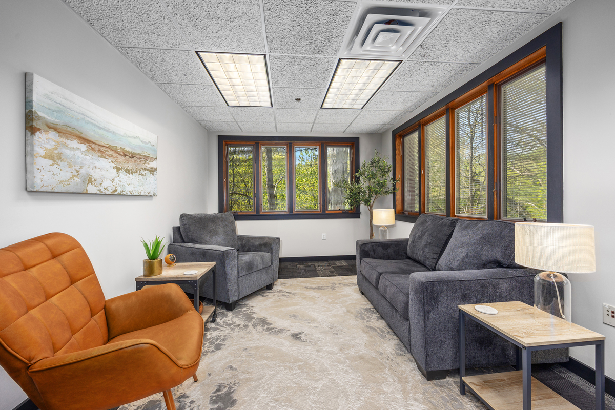 Therapy office with gray sofa, leather chair, and large windows