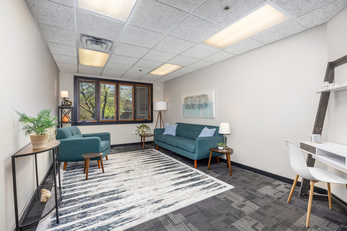 Therapy office with teal sofa and window view