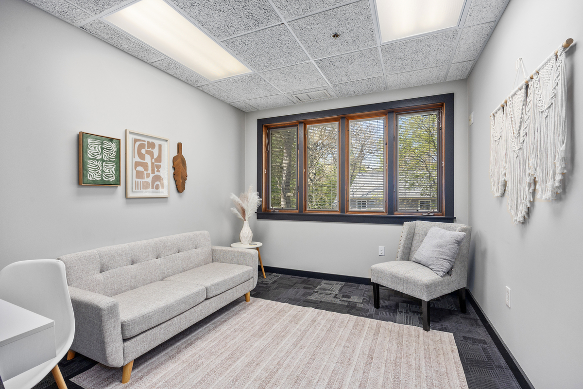 Therapy office with a gray sofa, accent chair, and framed artwork
