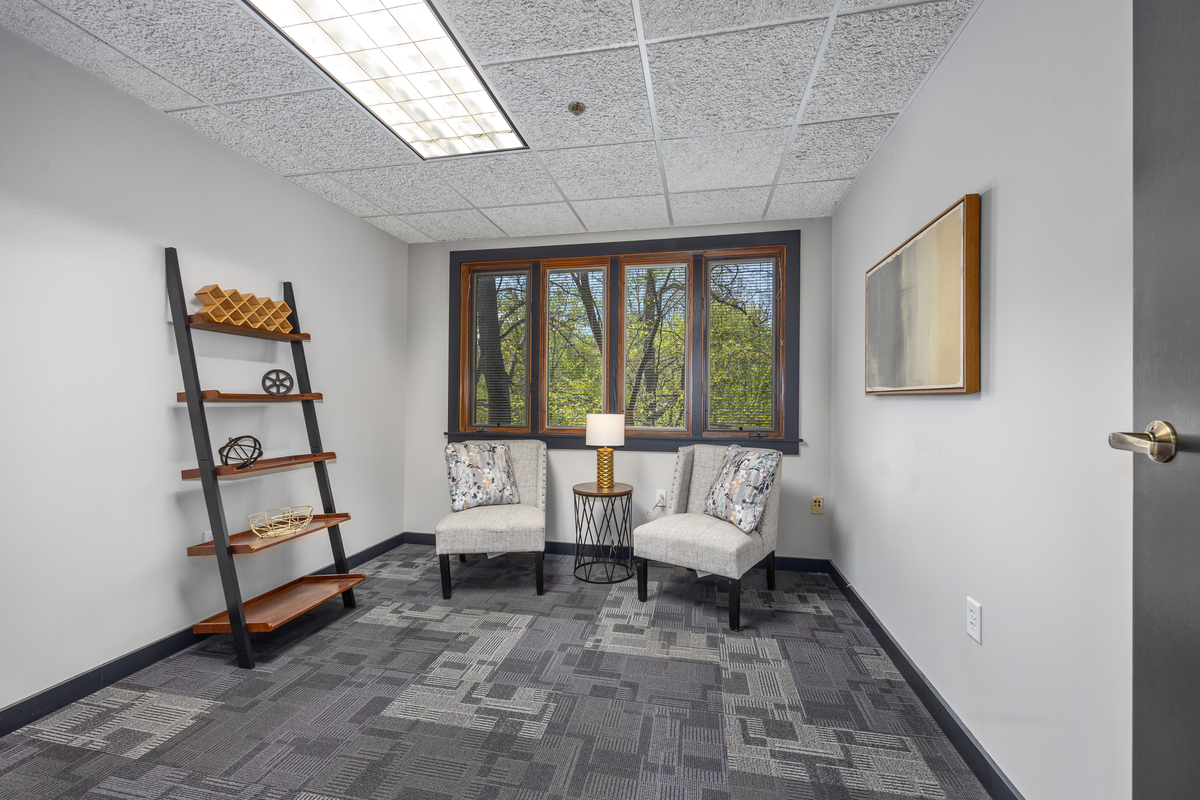 Therapy office with two upholstered chairs beneath a large window
